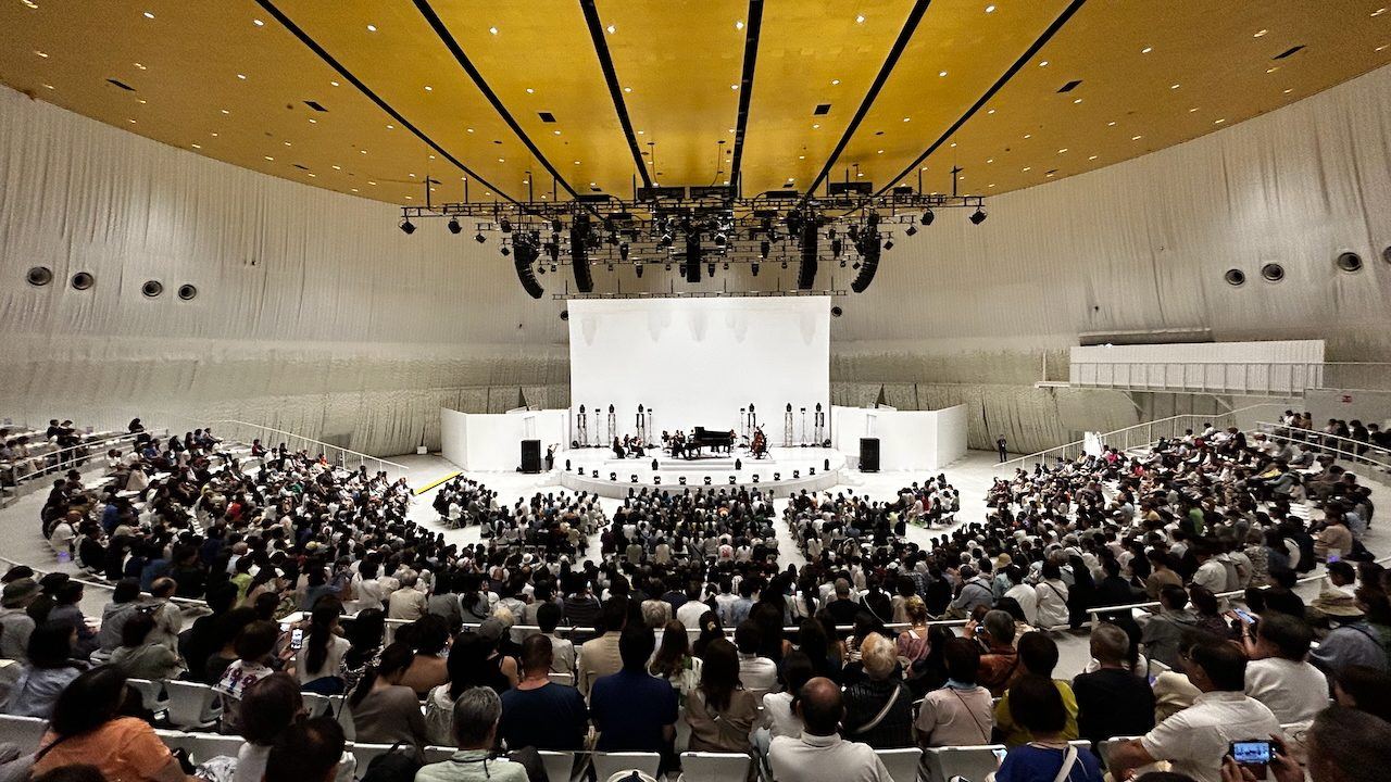 Chamber concert in a white-draped hall with a full audience