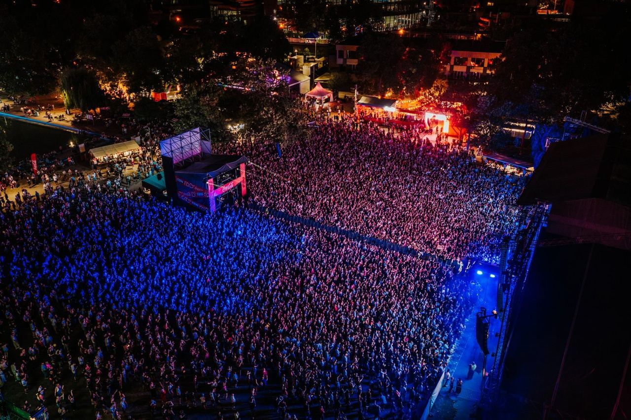 Aerial view of a packed festival crowd in blue and pink light