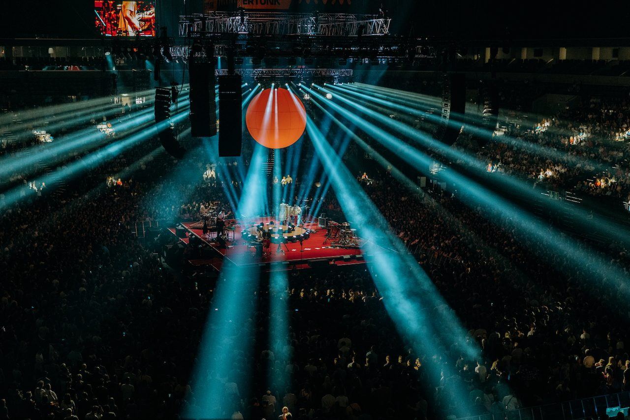 Arena show with a giant orange sphere above a centre stage